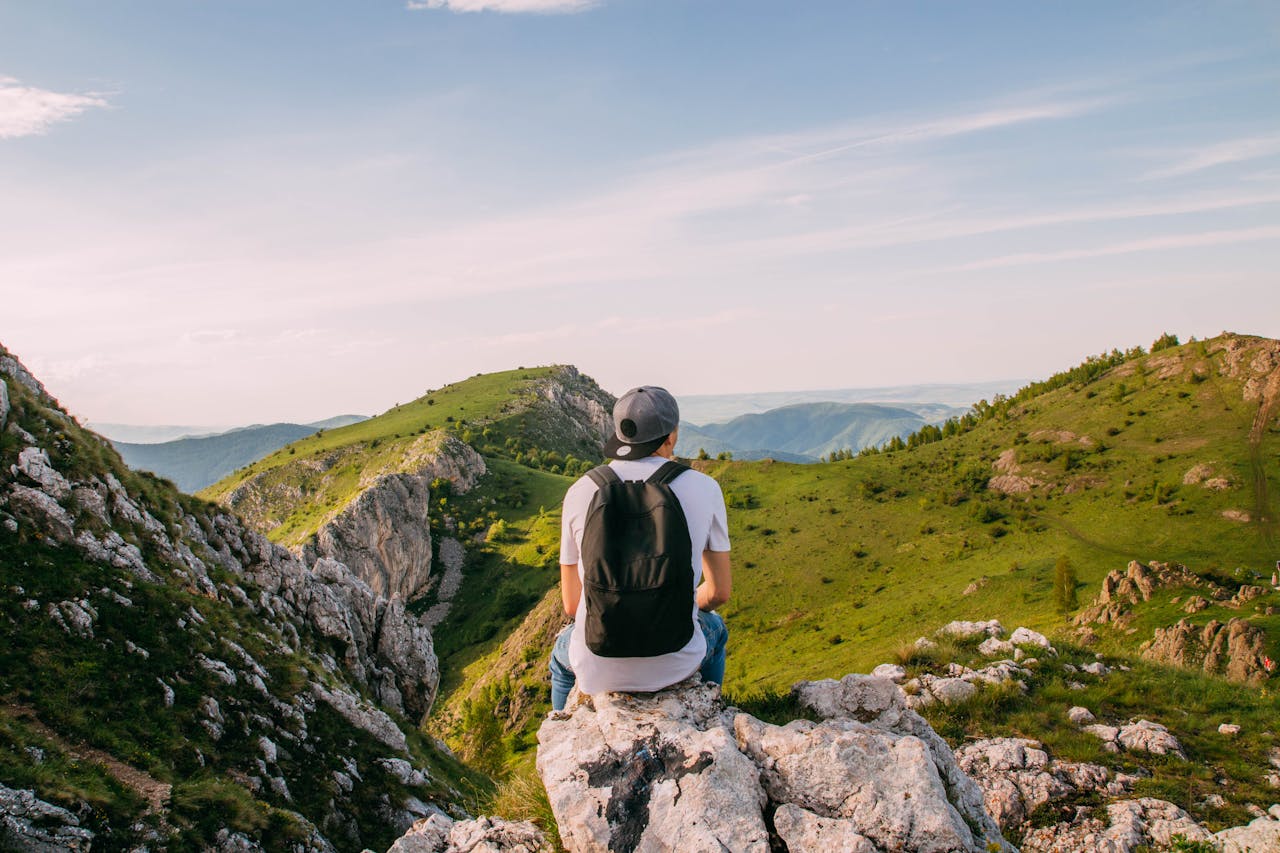 Man sitting on rocks with a scenic mountain view in Rimetea, Romania, perfect for adventurers.