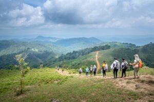 Group of hikers trekking through picturesque mountain landscape on a cloudy day.