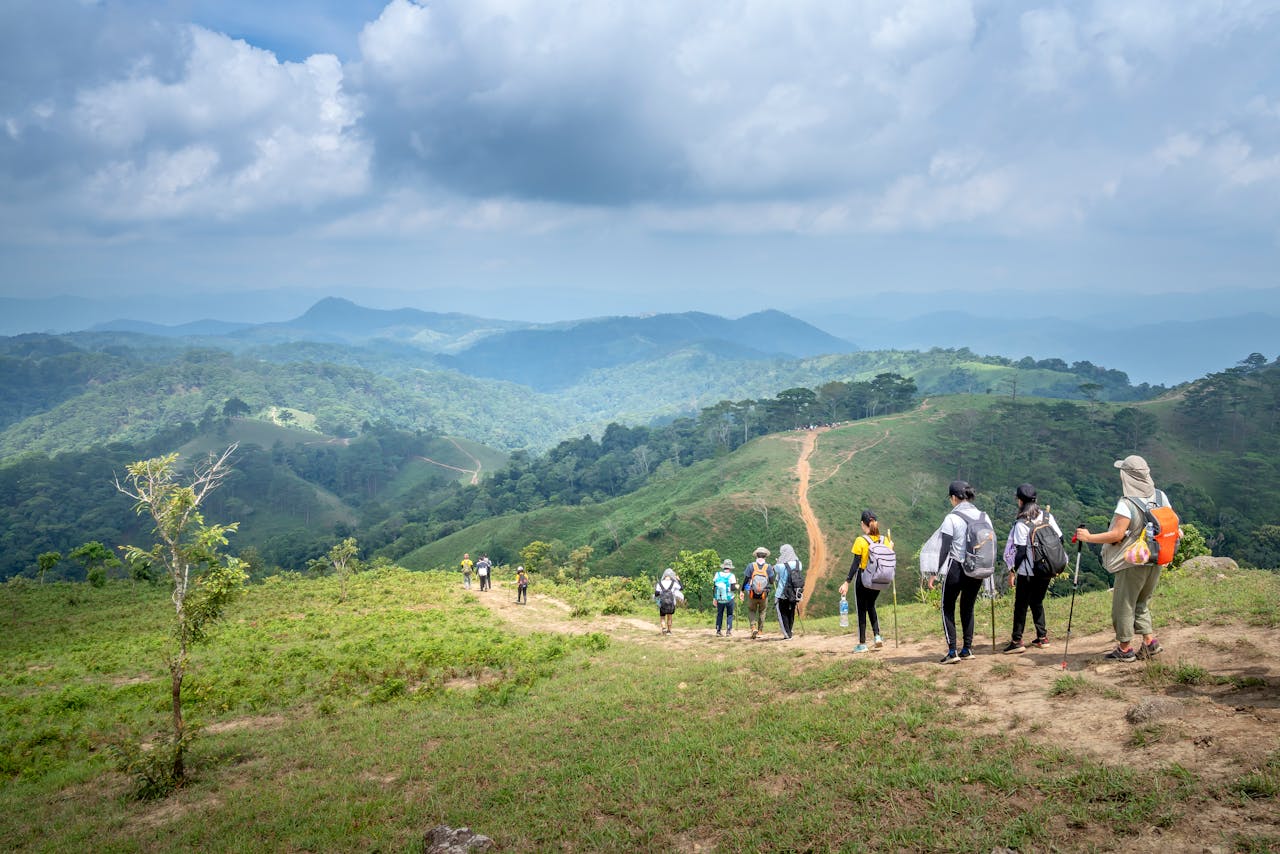 Group of hikers trekking through picturesque mountain landscape on a cloudy day.